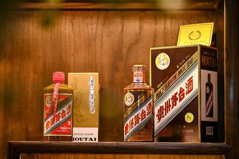 琥珀色の酒液のボトルと化粧箱が並ぶ木格の棚
